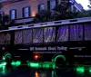 The image shows the Old Savannah Ghost Trolley on a rainy evening with green lighting reflecting off the wet ground creating a moody and atmospheric setting