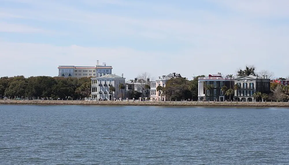 The image depicts a calm waterfront lined with stately homes against a clear sky