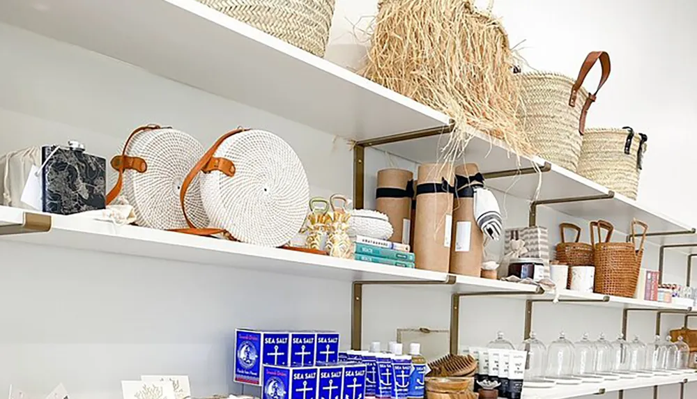 The image shows a neatly organized retail display featuring a variety of items such as woven baskets towels books and home decor