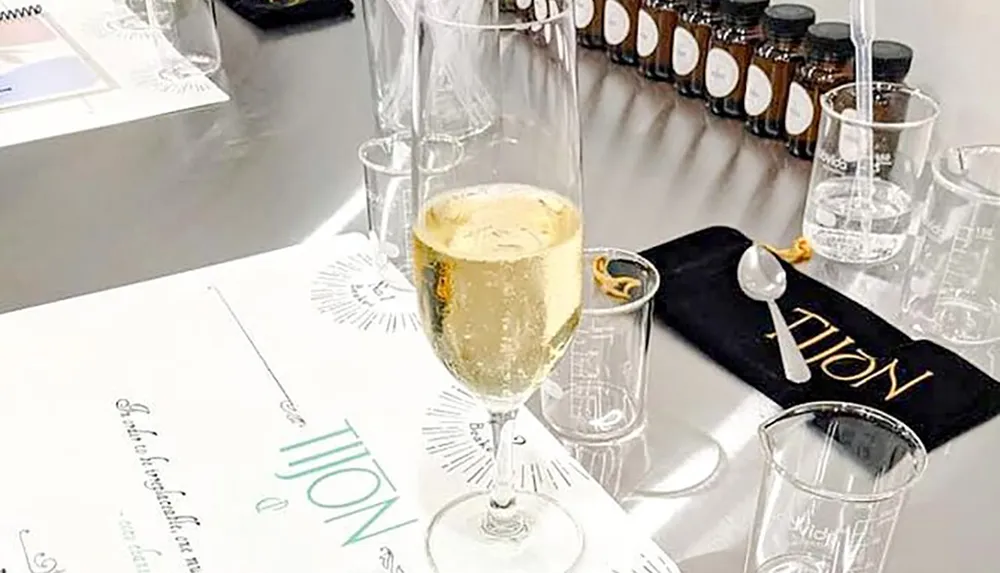 A glass of champagne is placed on a table alongside culinary equipment and a menu suggesting a fine dining or tasting event