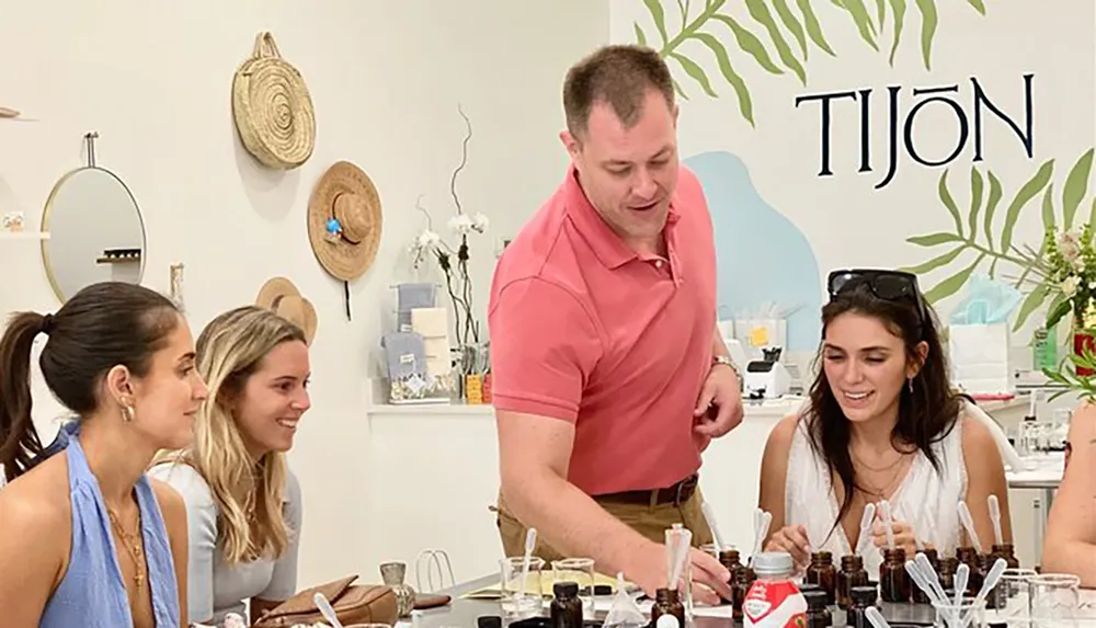 A group of people is engaging in a fragrance creation workshop with small vials and materials on the table observed by an instructor