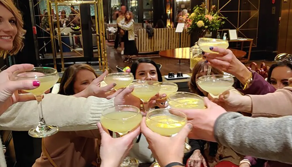 A group of people is cheerfully toasting with margarita glasses in a festive social setting