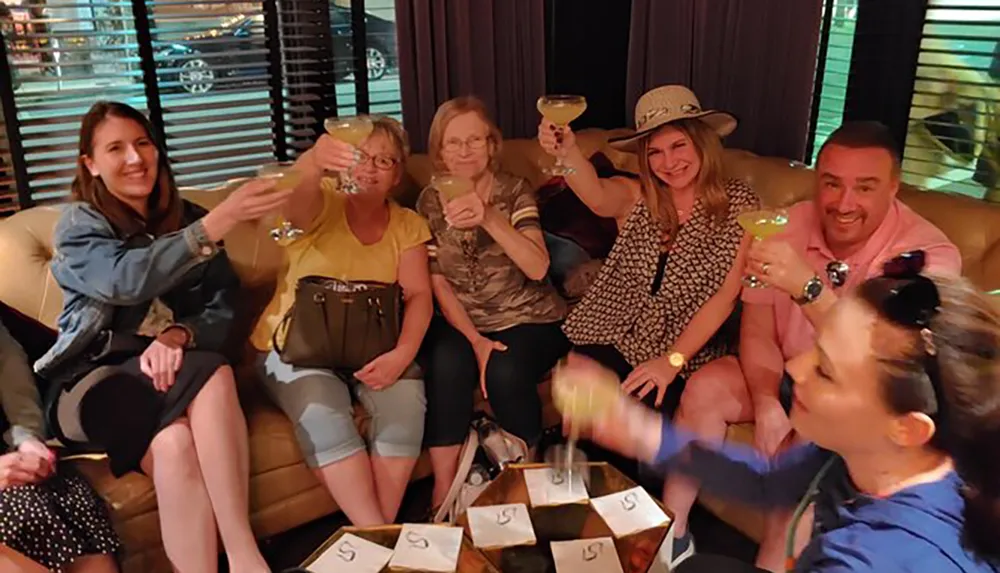 A group of people smiling and toasting with drinks appears to be enjoying a social gathering