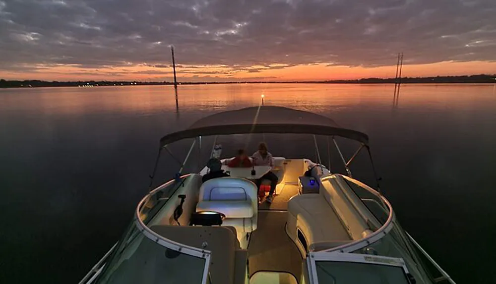 Two people are enjoying a tranquil evening on a boat with a stunning sunset in the background