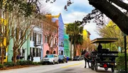 A horse-drawn carriage travels along a street lined with colorful buildings, showcasing a blend of historical charm and vibrant architecture.
