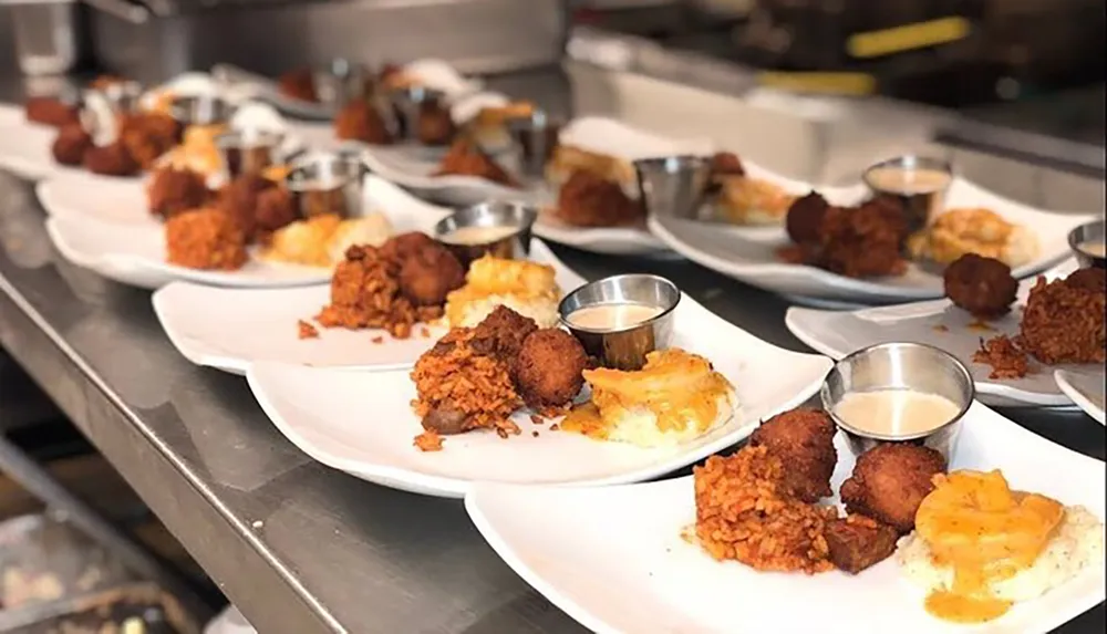 The image shows a series of plates with fried chicken sides and sauce lined up on a counter likely in a restaurants kitchen ready to be served