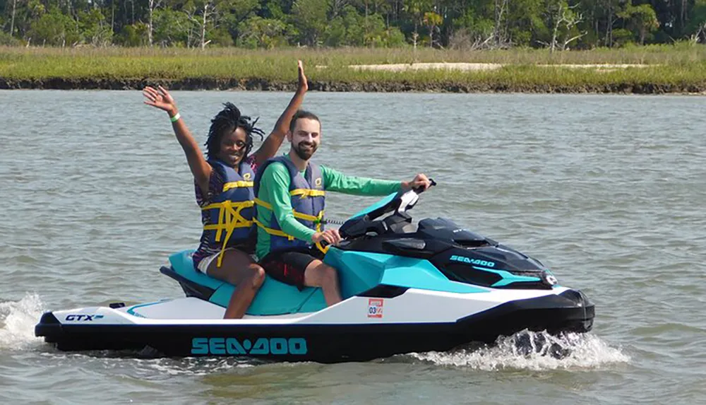 Two people are happily riding a Sea-Doo jet ski on a sunny day with the woman raising her hand in excitement