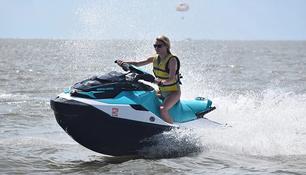 A person is riding a jet ski on a body of water creating a spray of water around them