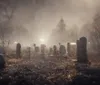 The image depicts a misty and eerie graveyard at twilight with light filtering through the haze to illuminate the tombstones scattered amongst the leaf-strewn ground