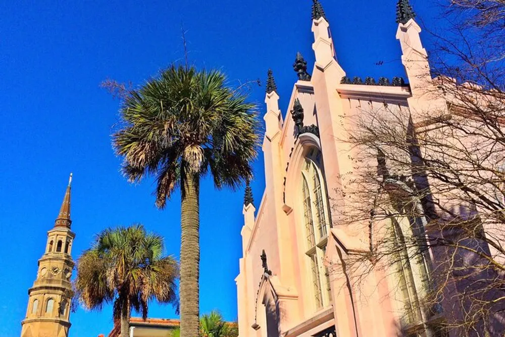 The image shows a historic church with a towering spire beside a palm tree against a clear blue sky
