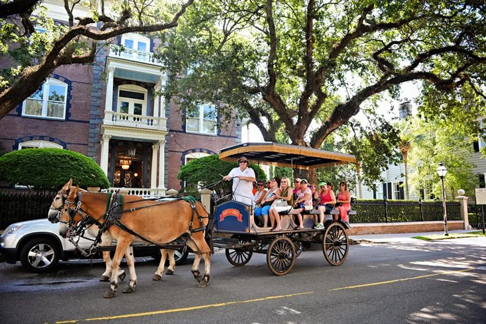 A horse-drawn carriage full of tourists is passing by a stately home on a sunny day creating a scene blending modern tourism with historical transport