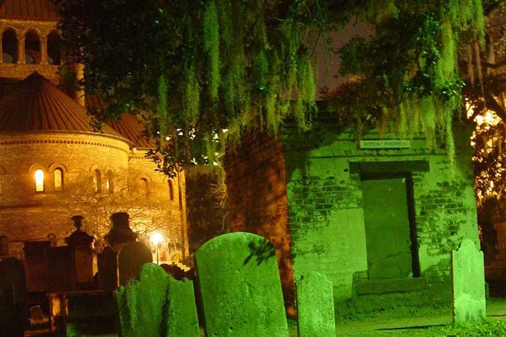 An eerie green light illuminates an old cemetery with moss-draped trees weathered headstones and a crypt at night