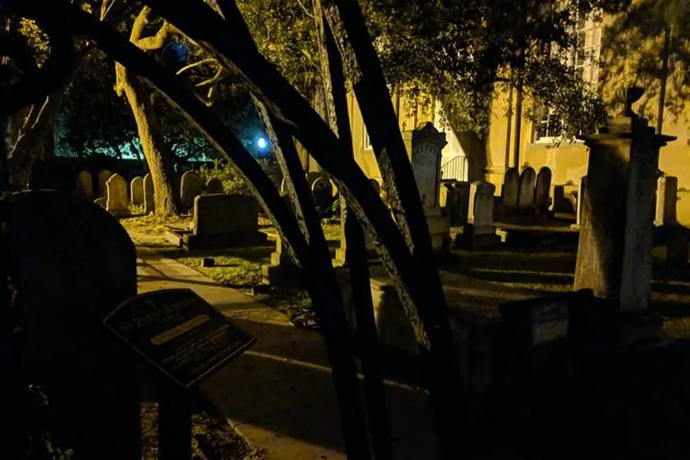 The image shows a dimly lit cemetery at night creating a somber and possibly eerie atmosphere