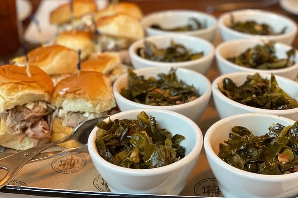 The image features several pulled pork sandwiches and multiple bowls of collard greens served on a tray suggestive of a Southern-style meal