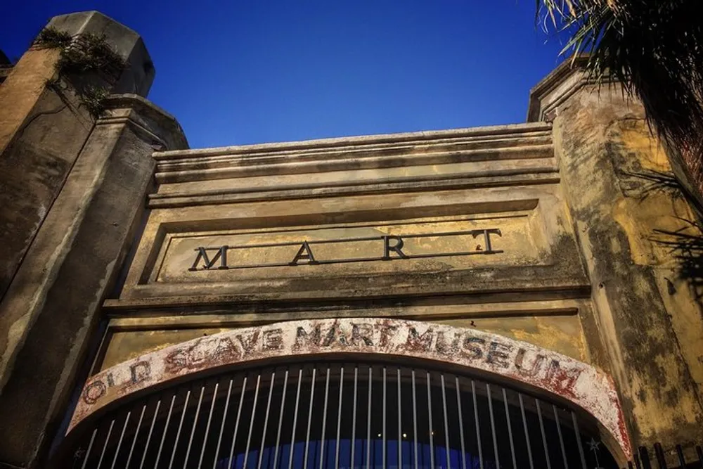 The image displays the weathered facade of a building with the word MART prominently displayed indicating the structures likely historical commercial use under a blue sky
