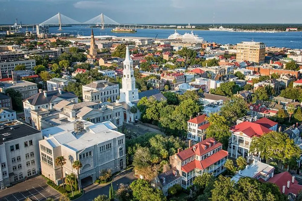 The image shows a panoramic aerial view of Charleston South Carolina with historic buildings lush greenery a distant bridge and a ship on the water