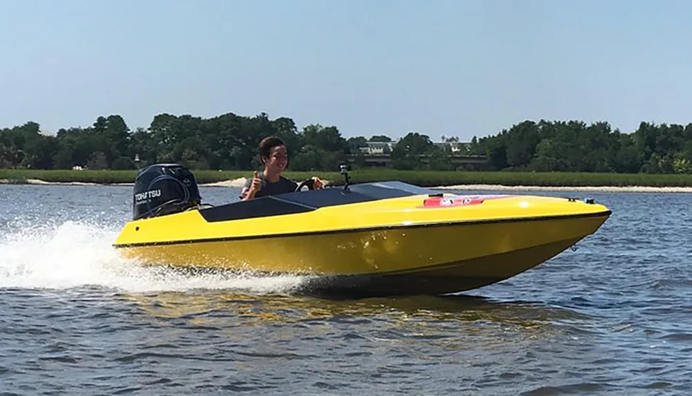 A person is driving a yellow speedboat on a body of water creating a wake behind