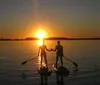 Two people are enjoying paddleboarding in calm waters with smiles on their faces