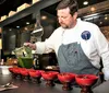 A chef in a casual restaurant is serving a dish to a customer across the bar in a cozy dimly lit dining atmosphere