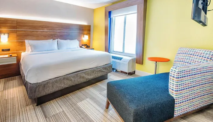 The image shows a colorful hotel room with a large bed vibrant decor and modern amenities