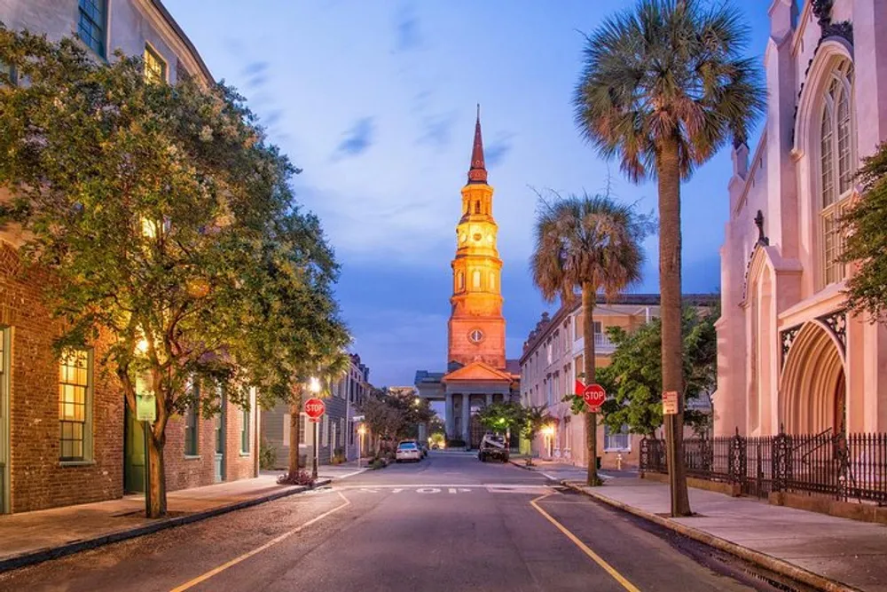 A quiet evening street scene with the warm glow of a historic church steeple standing tall against a dusky sky flanked by lush trees and traditional architecture