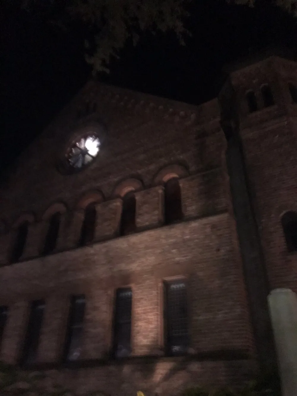 The image shows a dimly lit old brick building at night possibly a church with a blurred effect