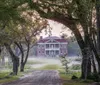 A stately red-brick building stands at the end of a tree-lined gravel path shrouded in a light morning mist