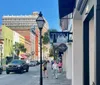 Pedestrians stroll down a sunny picturesque street lined with historical buildings and storefronts