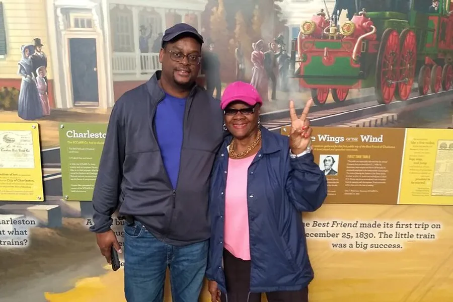 A man and a woman are posing for a photo together with a historical train mural in the background.