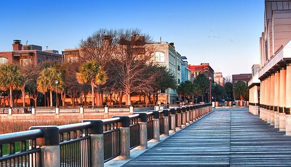 This image shows a serene waterfront walkway lined with palm trees and historic buildings bathed in the warm glow of the setting or rising sun
