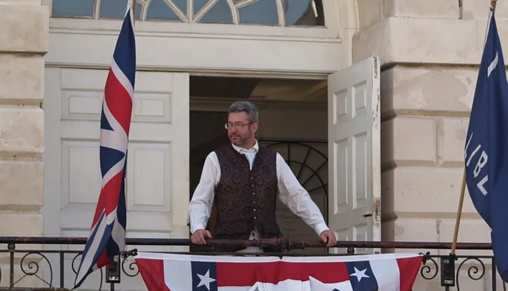 A person stands on a balcony with historical American flags suggesting a scene from a historical reenactment or celebration