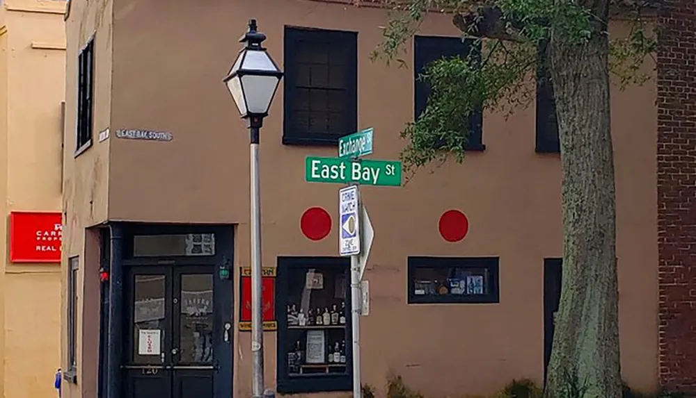 A street corner with a traditional lamp post and a sign that reads East Bay St and Exchange St in front of a building with two large red circular shapes that resemble abstract art or decorative features