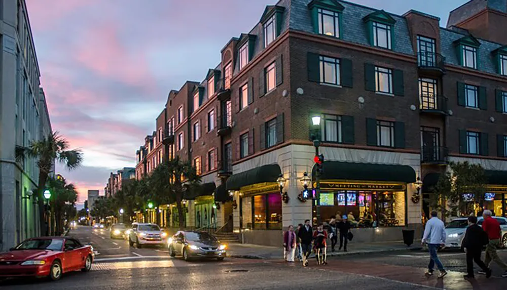 The image depicts an early evening street scene with pedestrians cars and a vibrant twilight sky in a town setting with brick buildings and shops