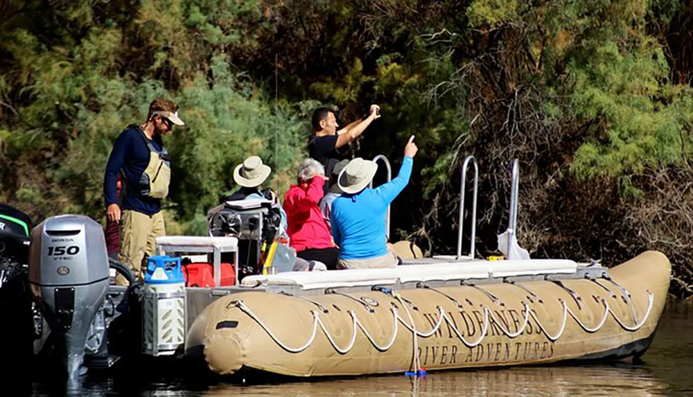 A group of people enjoy a guided tour on a large inflatable boat on a calm river surrounded by woodland