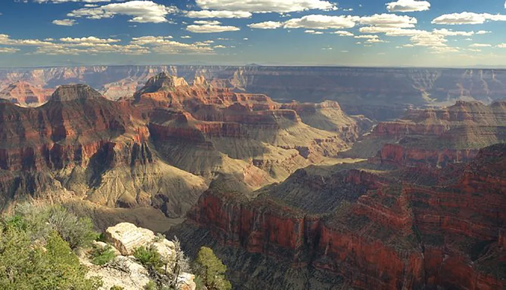 The image depicts the vast layered rock formations and deep canyons of the Grand Canyon under a partly cloudy sky