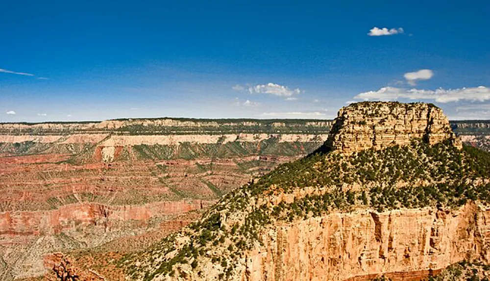 This image captures a vast rugged landscape showcasing a prominent cliff formation under a blue sky typical of the Grand Canyons striking geological features