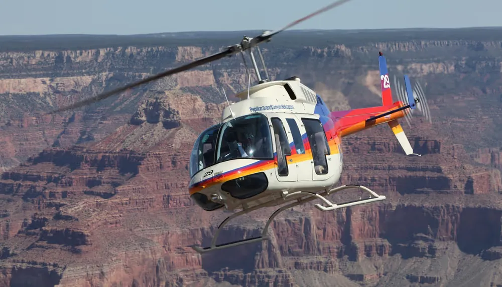 A helicopter is soaring in the sky with the picturesque backdrop of the Grand Canyon