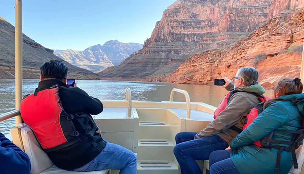 Passengers on a boat tour are admiring and photographing the scenic canyon walls around them