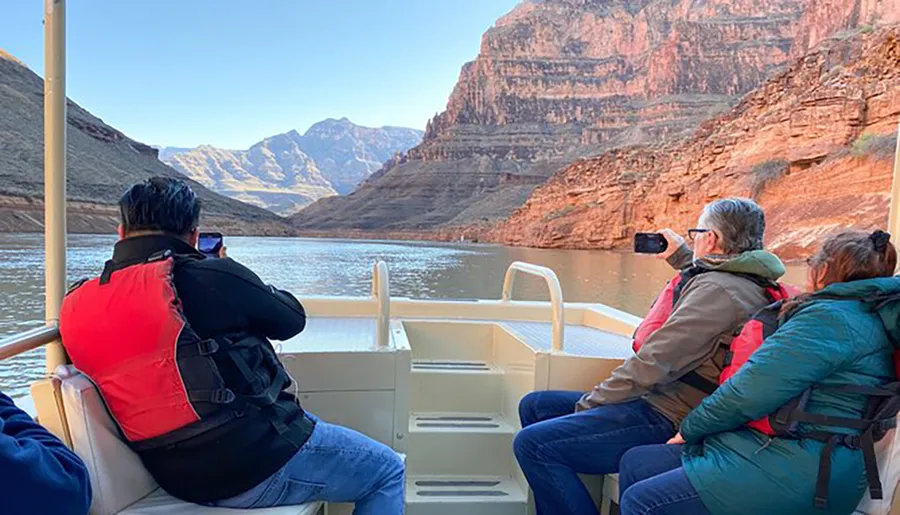 Passengers on a boat tour are admiring and photographing the scenic canyon walls around them.