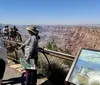 Tourists admire the expansive view of the Grand Canyon from a viewing platform with informational signage
