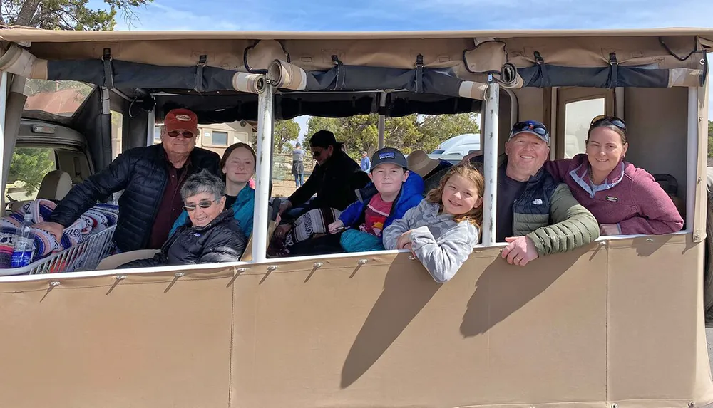 A group of seven people spanning multiple generations is smiling for a photo while seated inside a large canvas-covered open-air vehicle