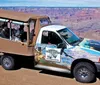 A group of tourists is riding in a vehicle with a Grand Canyon-themed wrap design touring near the edge of the canyon