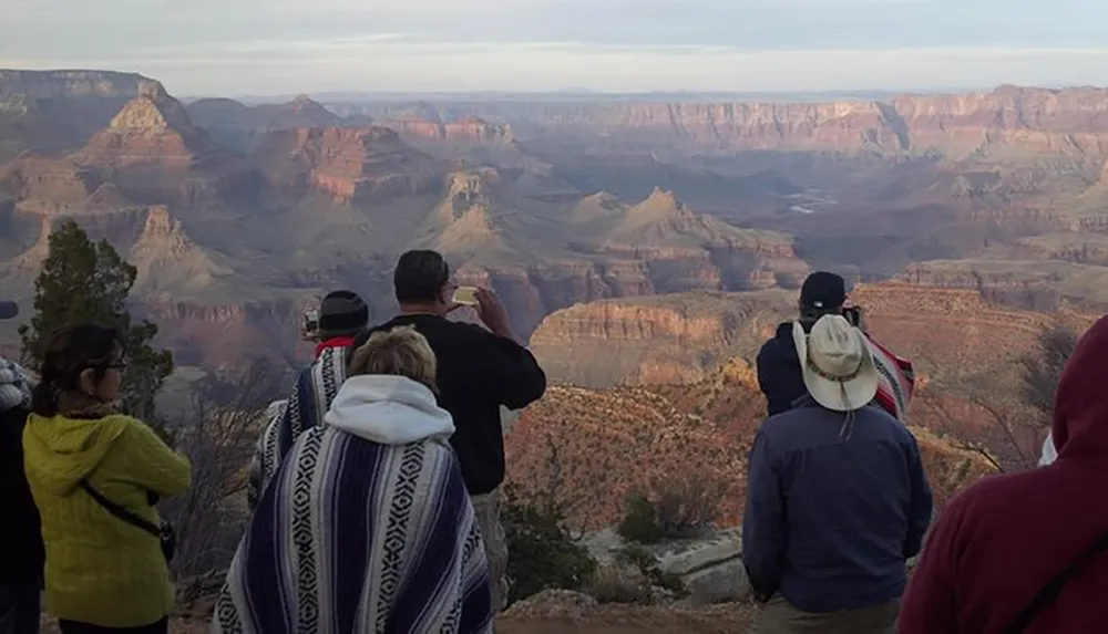 A group of people is admiring the view of the Grand Canyon at dusk capturing the moment with their cameras