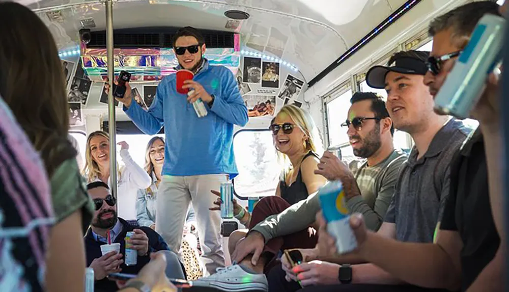 A group of joyful people is enjoying a party on a bus with drinks in their hands