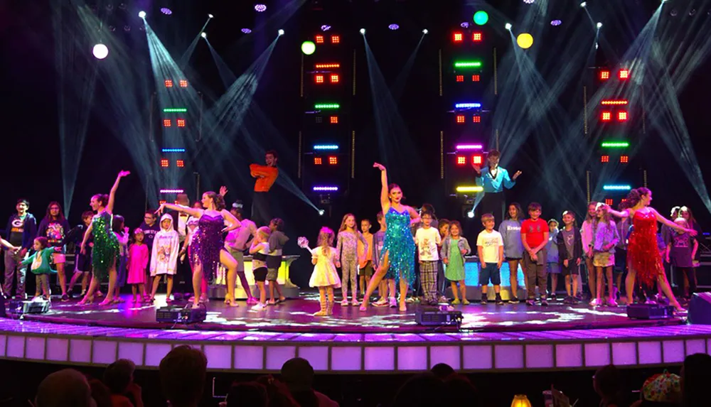 A group of children and performers are on a brightly-lit stage apparently participating in a lively and colorful interactive entertainment event