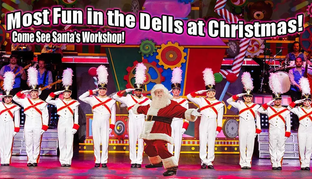 This image features a festive stage performance with a person dressed as Santa Claus dancing among performers in toy soldier costumes under a banner encouraging people to visit Santas Workshop for the Most Fun in the Dells at Christmas