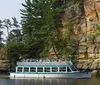 A boat named YELLOW THUNDER is carrying a group of passengers through a scenic waterway surrounded by lush forests and rock formations