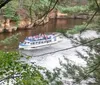 A boat named YELLOW THUNDER is carrying a group of passengers through a scenic waterway surrounded by lush forests and rock formations