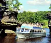 A tour boat named Chicagow is navigating between two large rock formations carrying passengers exploring a scenic waterway