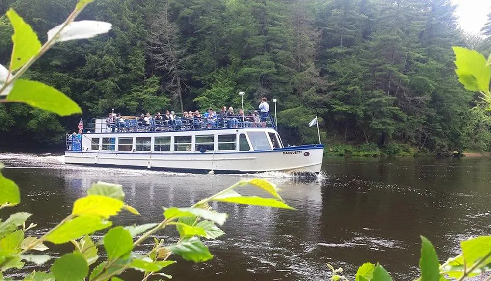 A group of passengers enjoys a scenic boat tour on a river surrounded by lush greenery